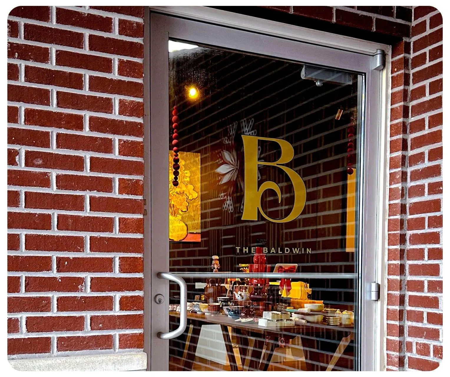 The gold B monogram on the front door of The Bar on Baldwin, set in red brick