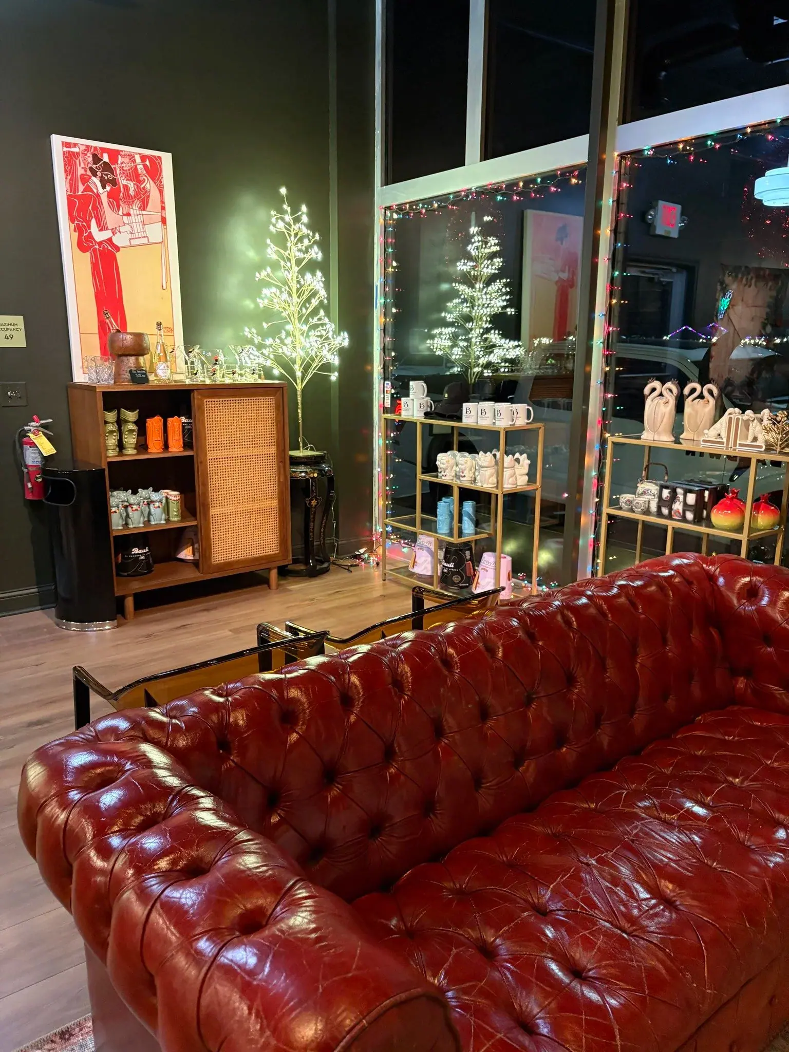 A cognac tufted leather Chesterfield sofa in the lounge at The Bar on Baldwin, with framed artwork and shelves of curiosities